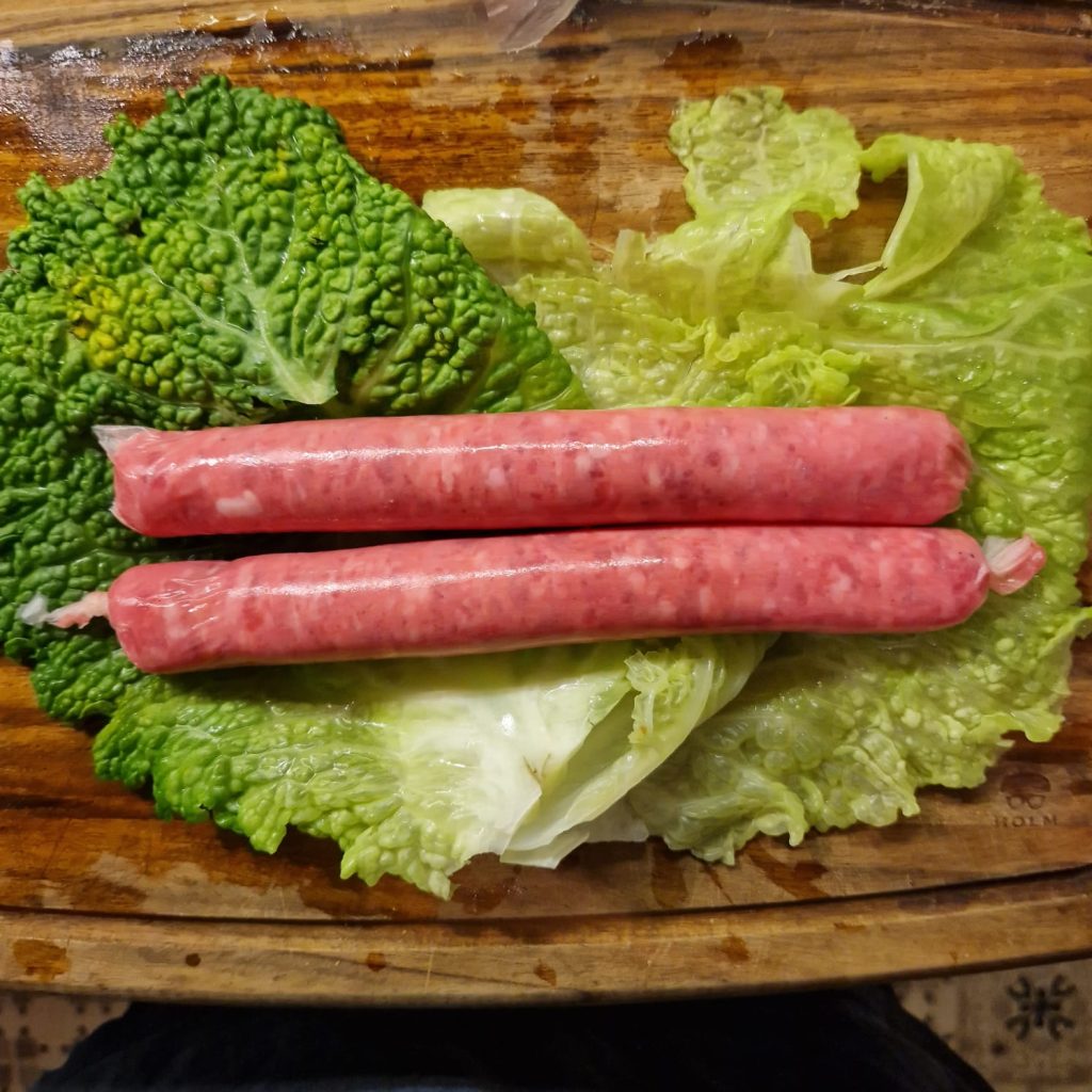 Sausages being wrapped in savoy cabbage